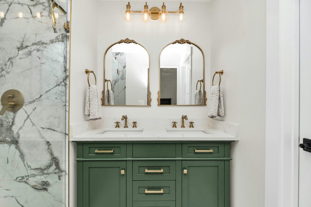 How Much Does a Bathroom Remodel Cost in Corpus Christi? (2025 Guide) 1 a bathroom with green cabinets and gold mirrors