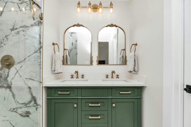 a bathroom with green cabinets and gold mirrors