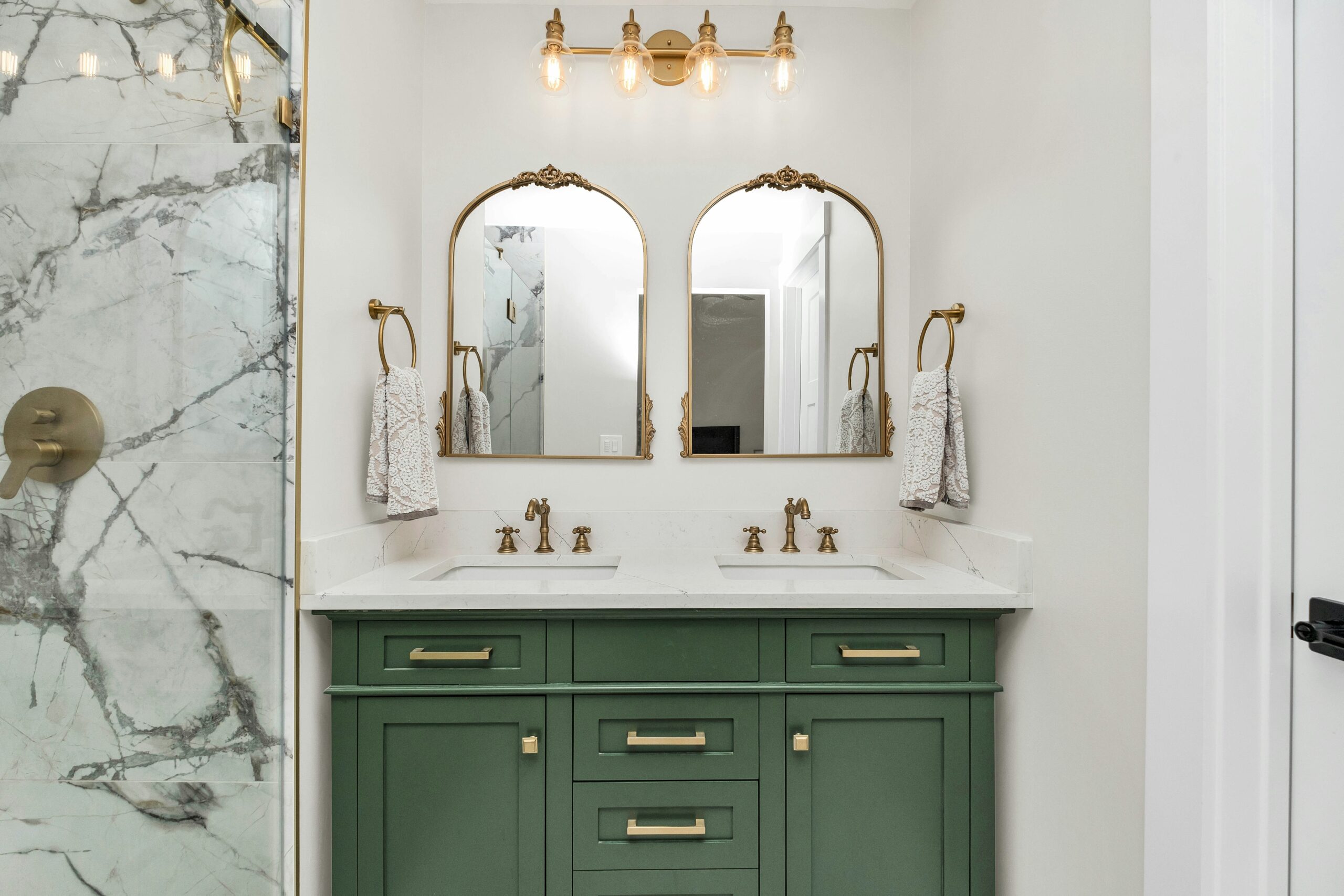a bathroom with green cabinets and gold mirrors